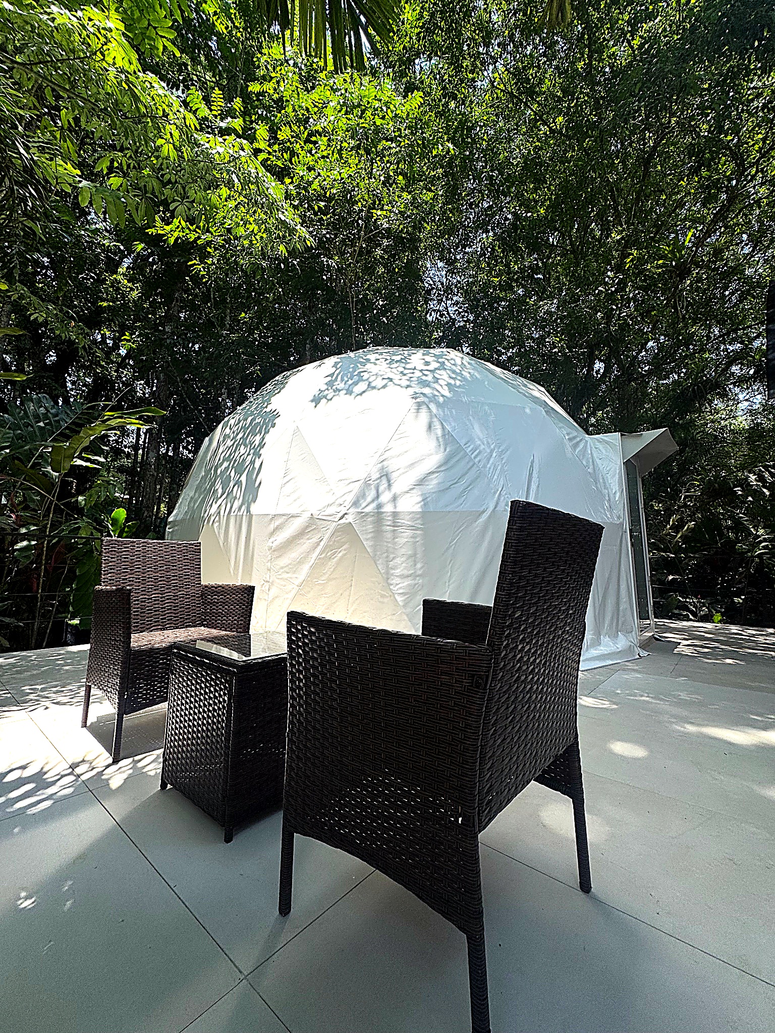 Private terrace with wicker dining set in front of a glamping dome.