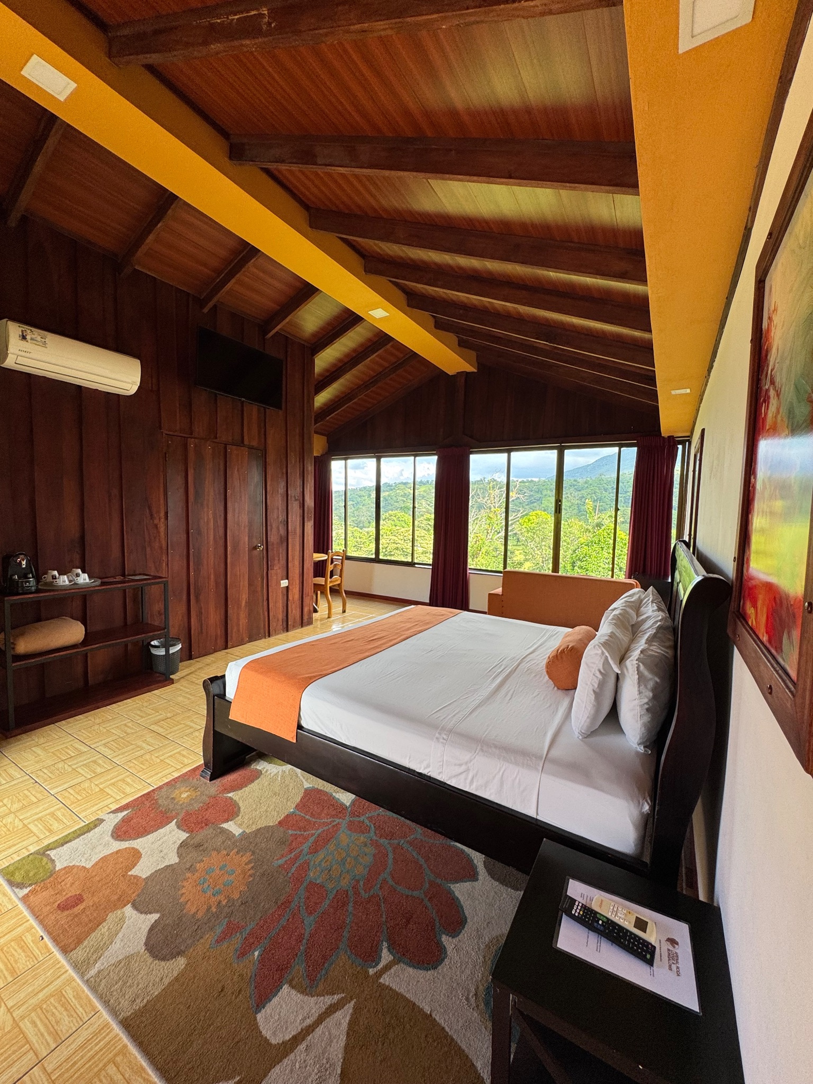 A deluxe room with wood ceiling, king bed, and broad picture windows.