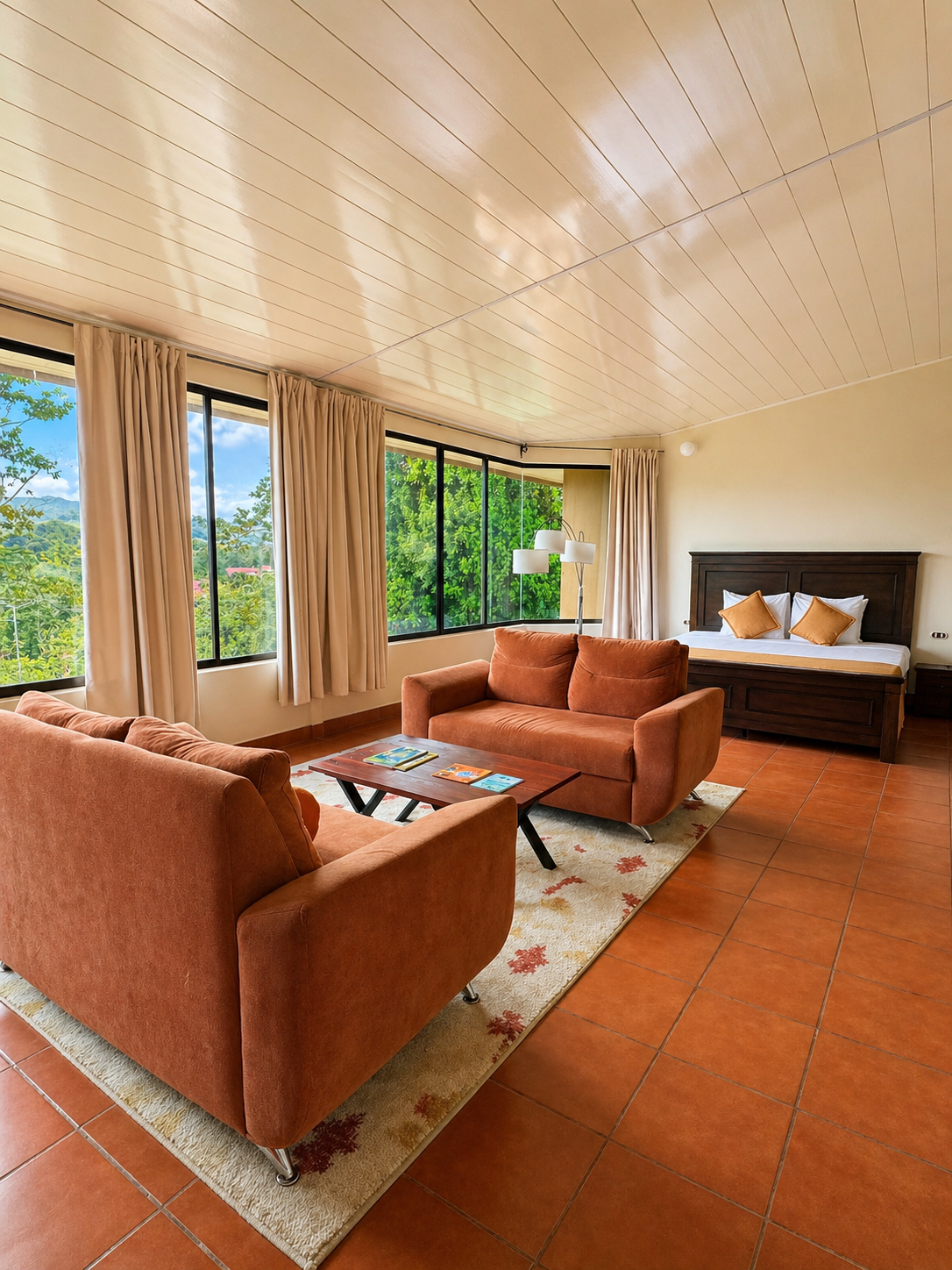 A spacious suite lounge and bed area with warm neutral furnishings.