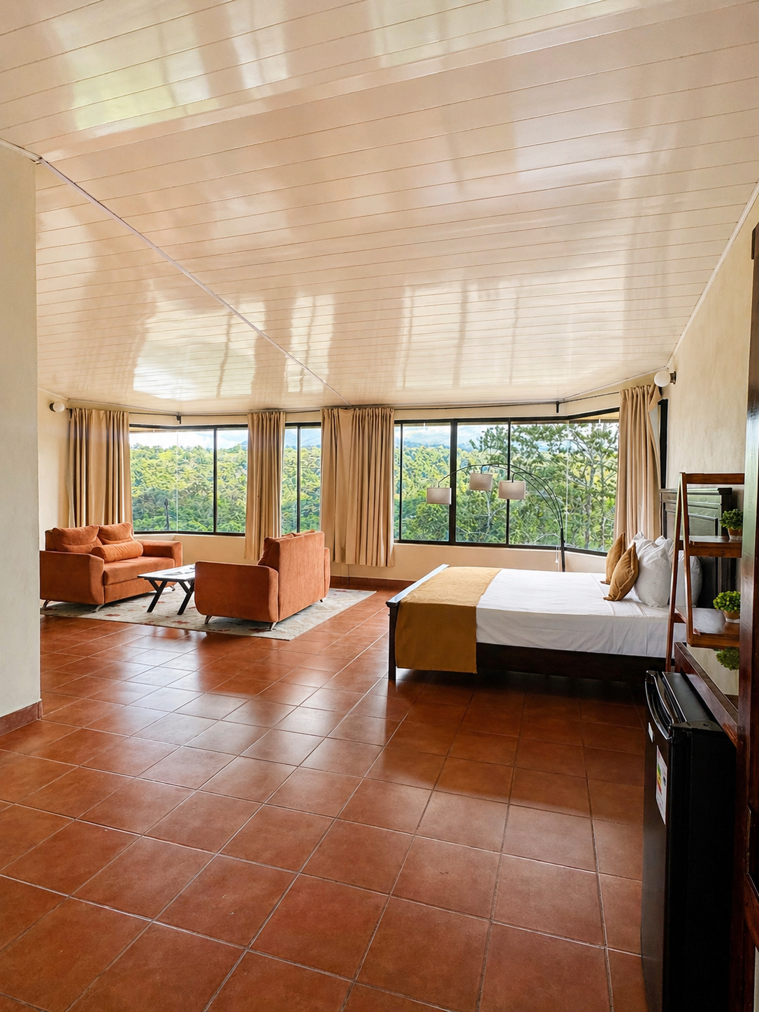 A wide suite interior with bed, seating area, and forest-facing windows.