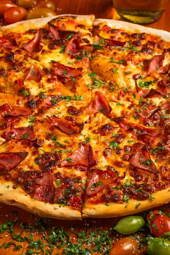 Artisan wood-fired pizza topped with ham and fresh herbs.