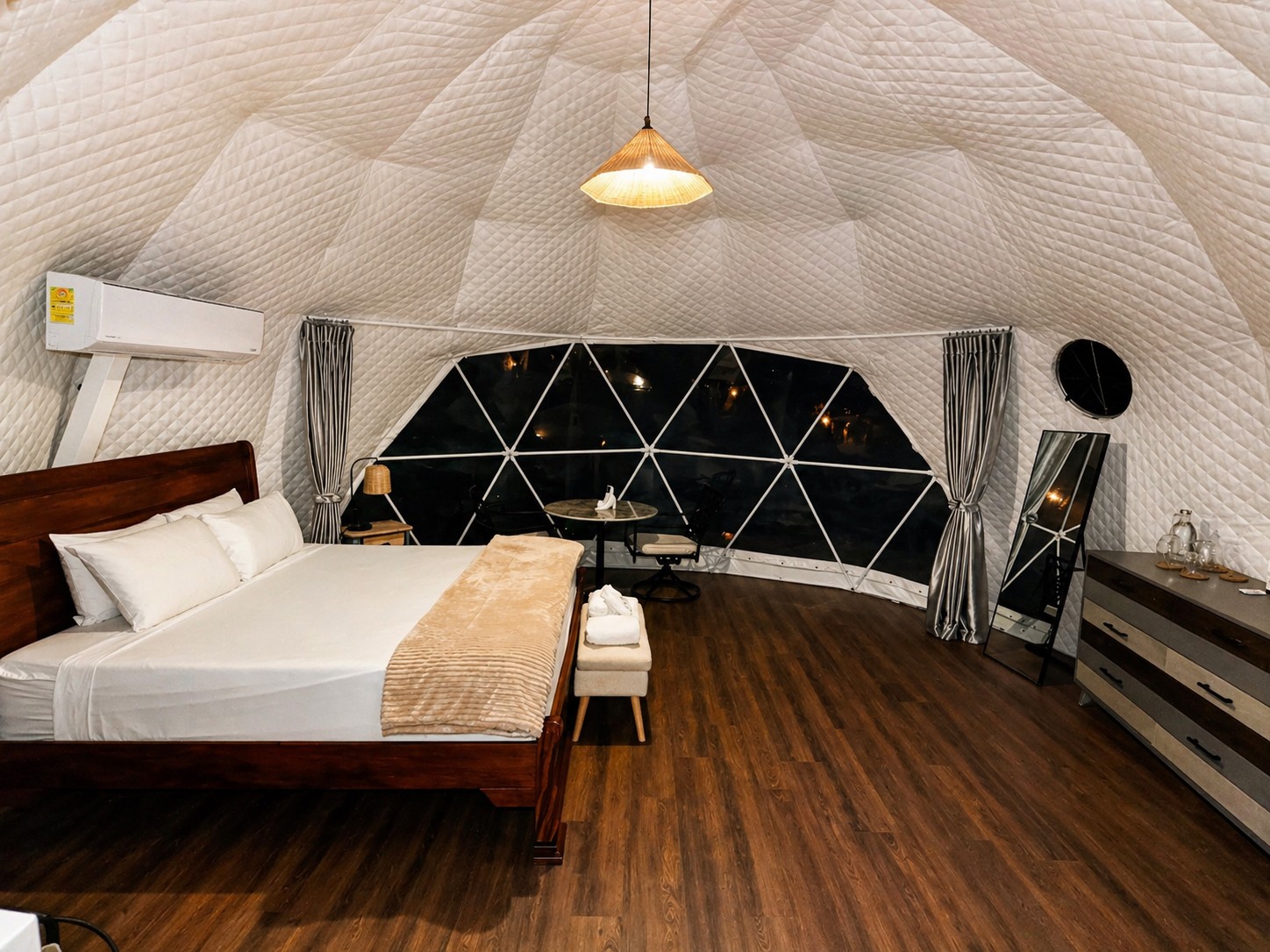 Premium dome interior with king bed and panoramic geodesic window at night.